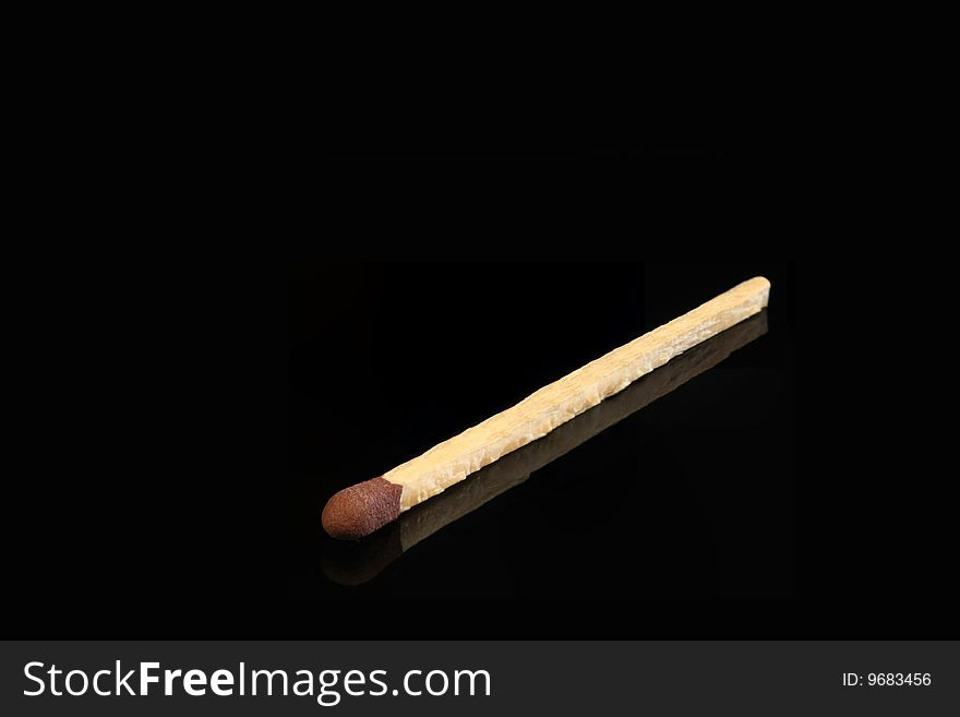 One match stick isolated on a black reflective surface. One match stick isolated on a black reflective surface