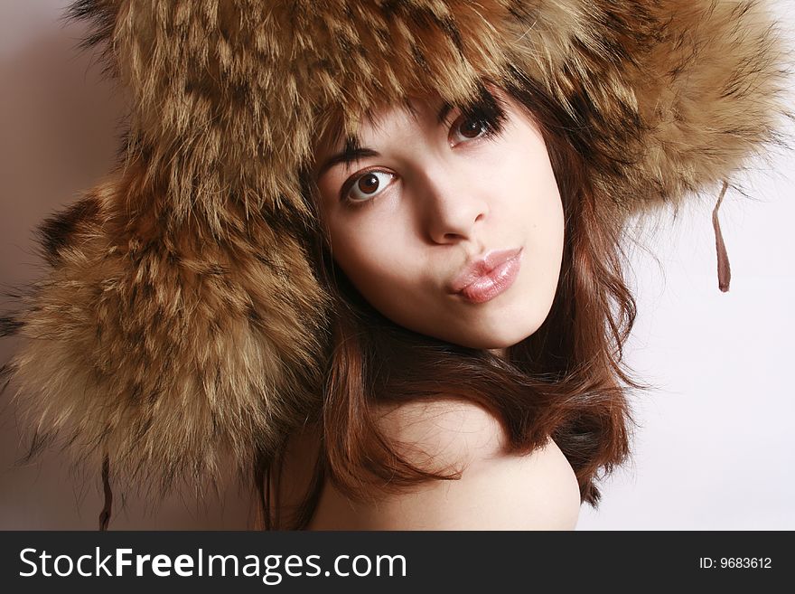 Portrait of the beautiful girl in a fur cap close up.