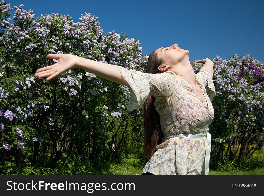 Young woman raise arms to the sky, blossom lilac background. Young woman raise arms to the sky, blossom lilac background
