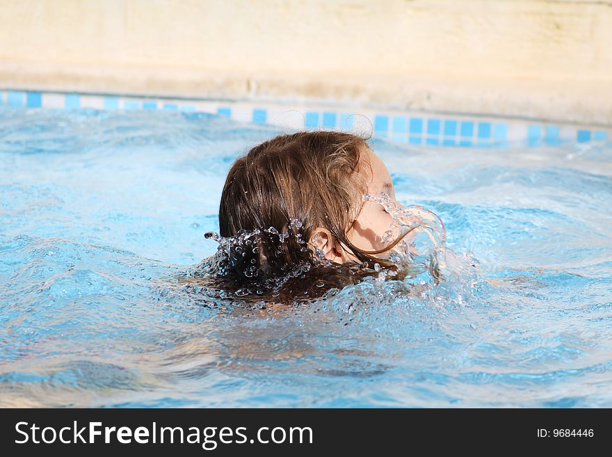 a caucasian child learning how to swim in a swimming pool with water splashed on her face. a caucasian child learning how to swim in a swimming pool with water splashed on her face