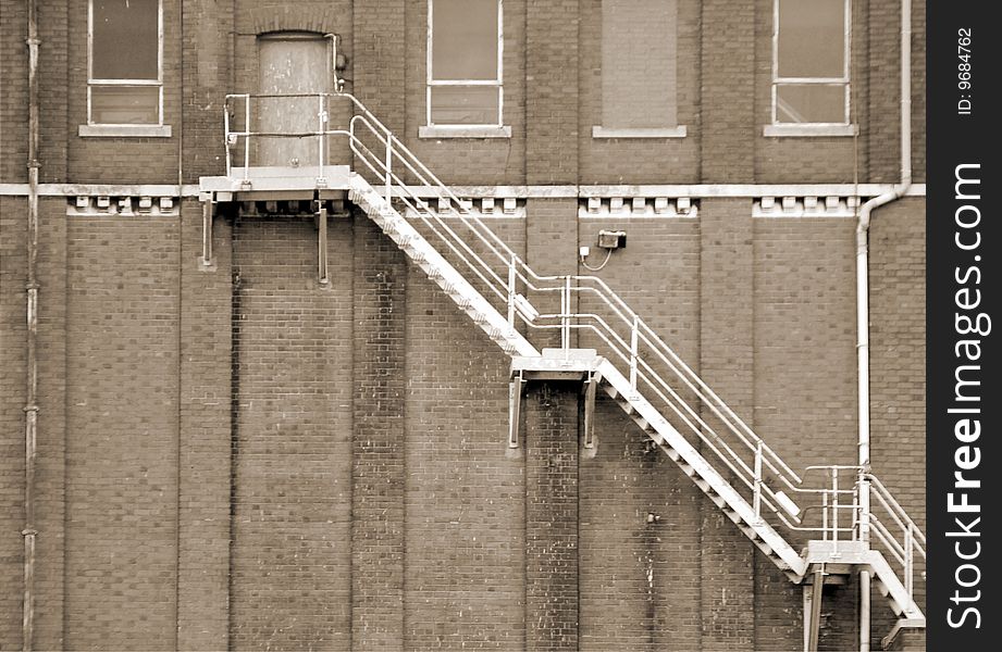 Sepia toned image of fire escape on brick building