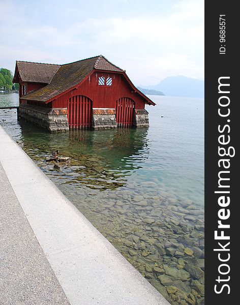 Red boat house on lake of luzern with mountains in background