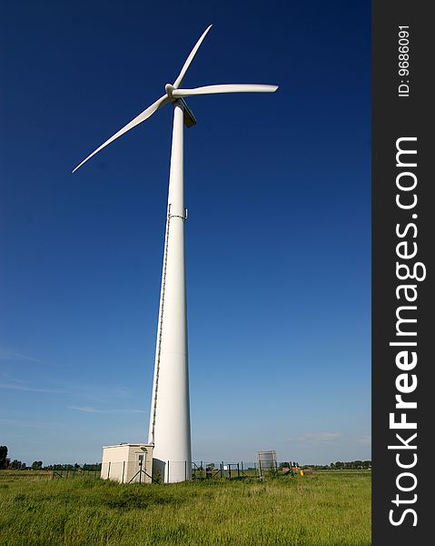 Photo of the wind generator in a grass, against the dark blue sky. Photo of the wind generator in a grass, against the dark blue sky