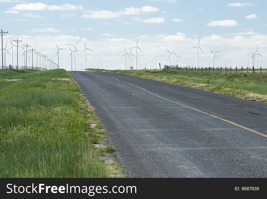 A wind farm on the horizon in Texas with heat waves from the highway