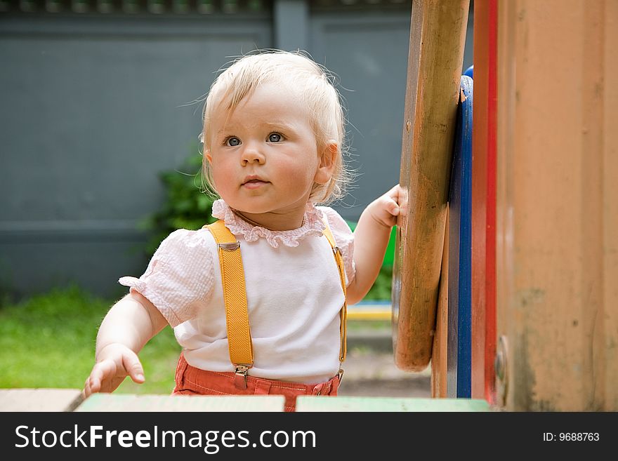 Little girl walks  on a playground in summer day