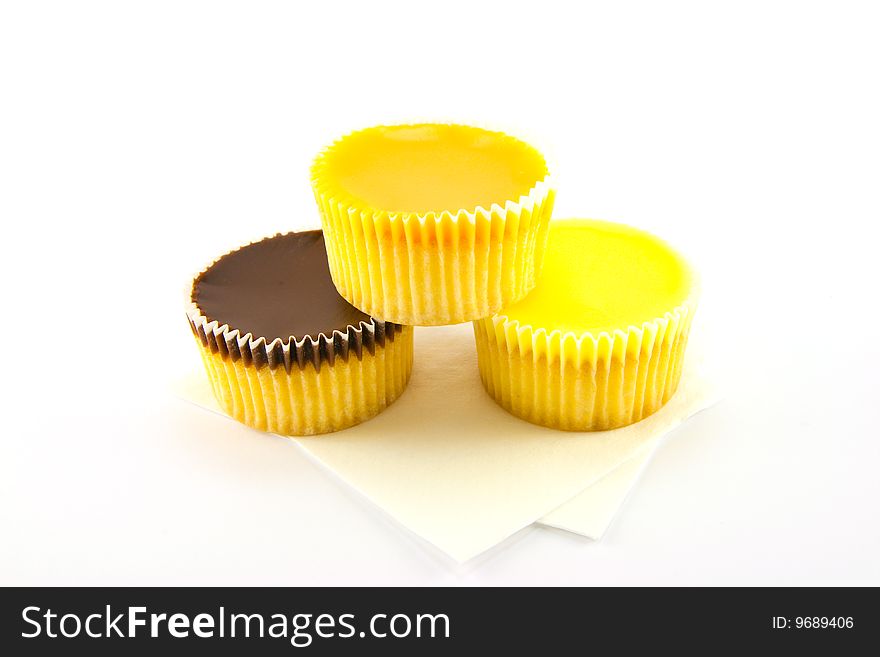 Three delicious looking cup cakes resting on two white napkins on a plain background. Three delicious looking cup cakes resting on two white napkins on a plain background