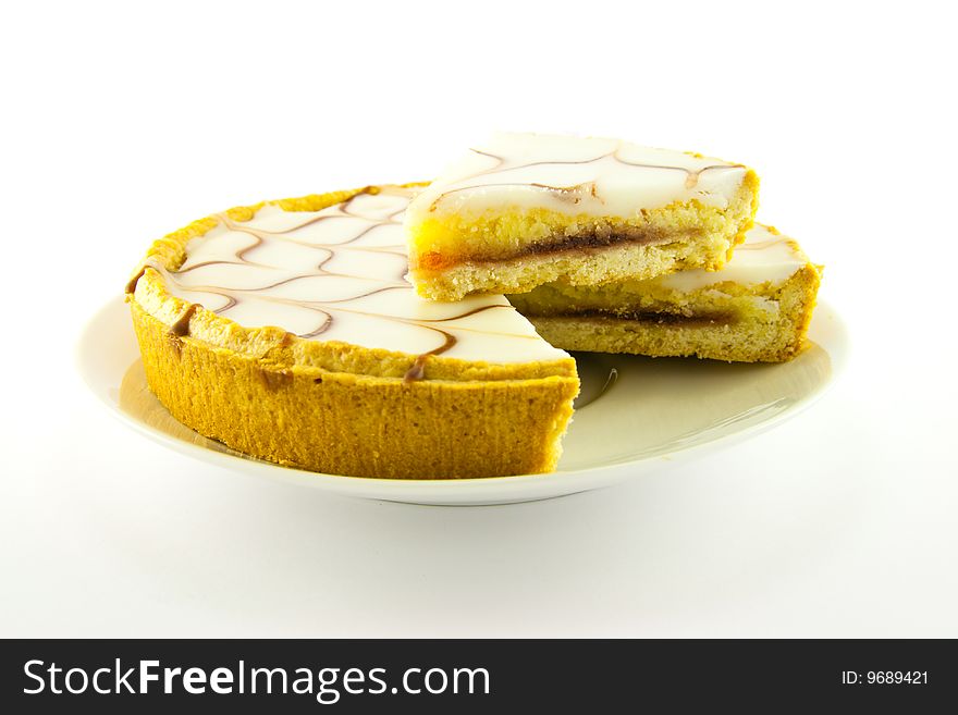 Delicious looking iced bakewell tart on a white plate with a plain background