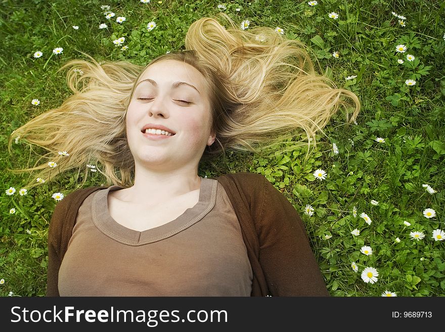 Happy woman lying in grass on a meadow with daisies