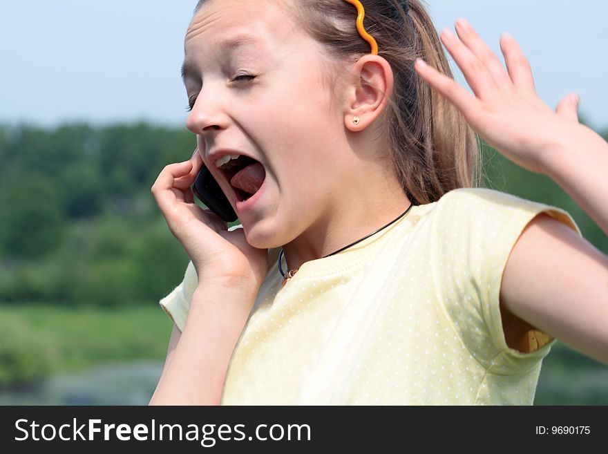 Close-up of nice young girl crying with mobile phone on nature background. Close-up of nice young girl crying with mobile phone on nature background