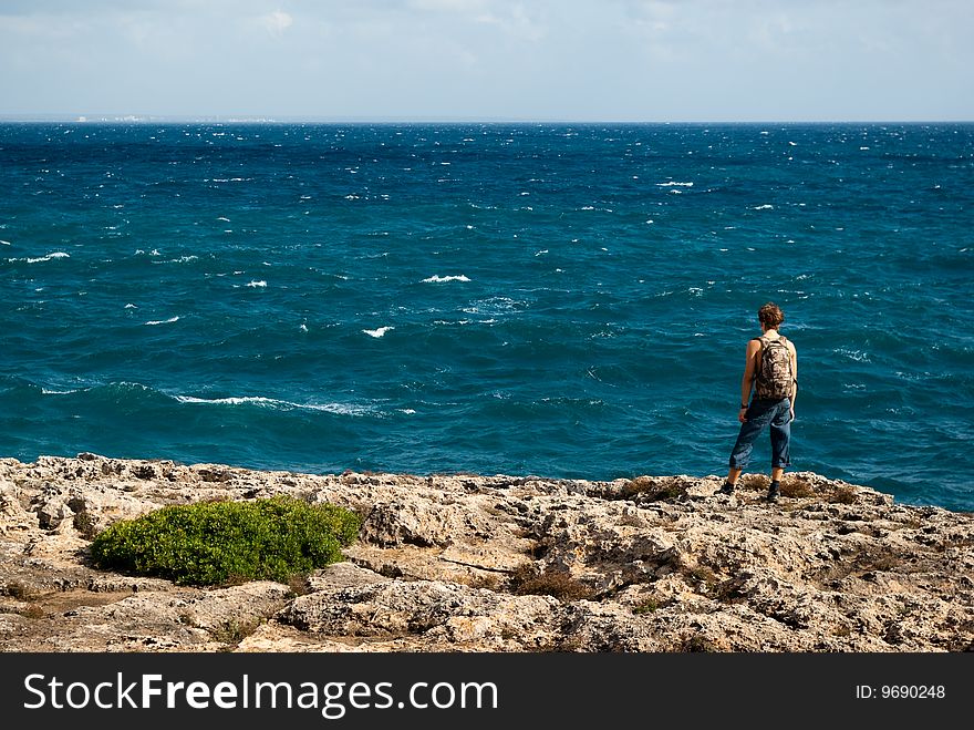 Young hiker standing on a rock an facing the Mediterranean sea. Young hiker standing on a rock an facing the Mediterranean sea