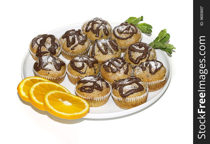 Plateful of delicious muffins decorated with slices of orange and mint leaves, high key photograph, isolated against white background