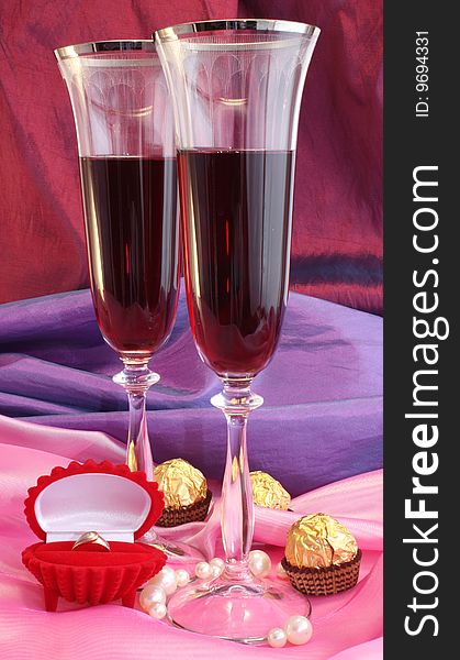 Two glasses with wine, a ring and chocolate. Two glasses with wine, a ring and chocolate