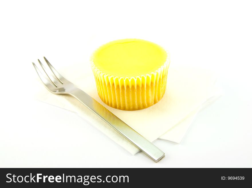 Delicious looking cup cake resting on two white napkins with a fork on a plain background