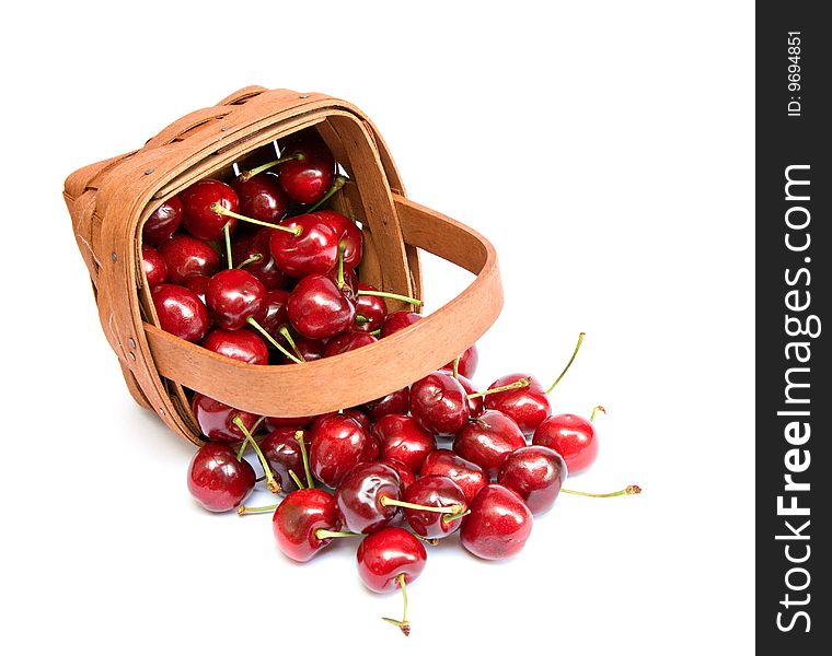 A basket of cherries spilled agains white background.