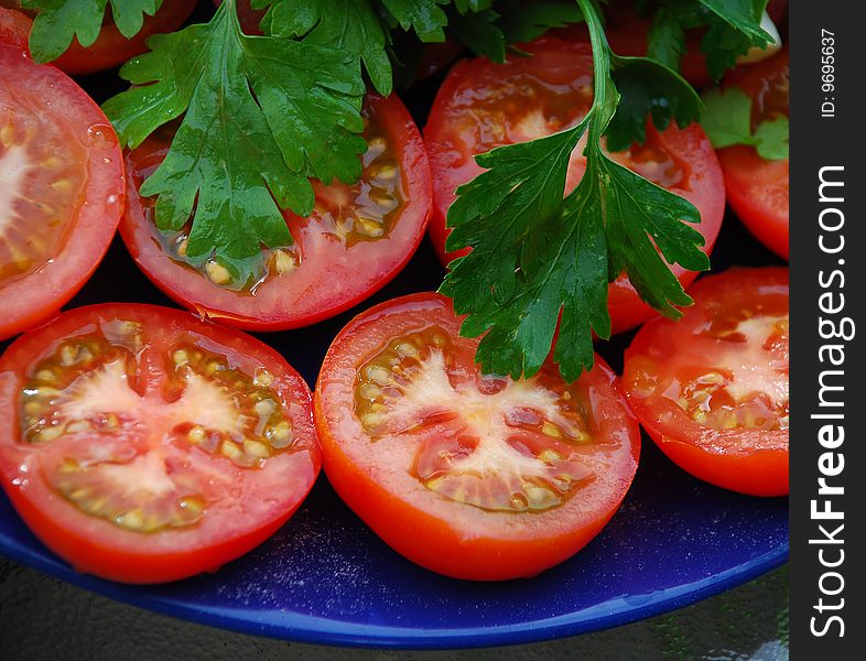 Halves of tomatoes on a dark blue dish. Halves of tomatoes on a dark blue dish