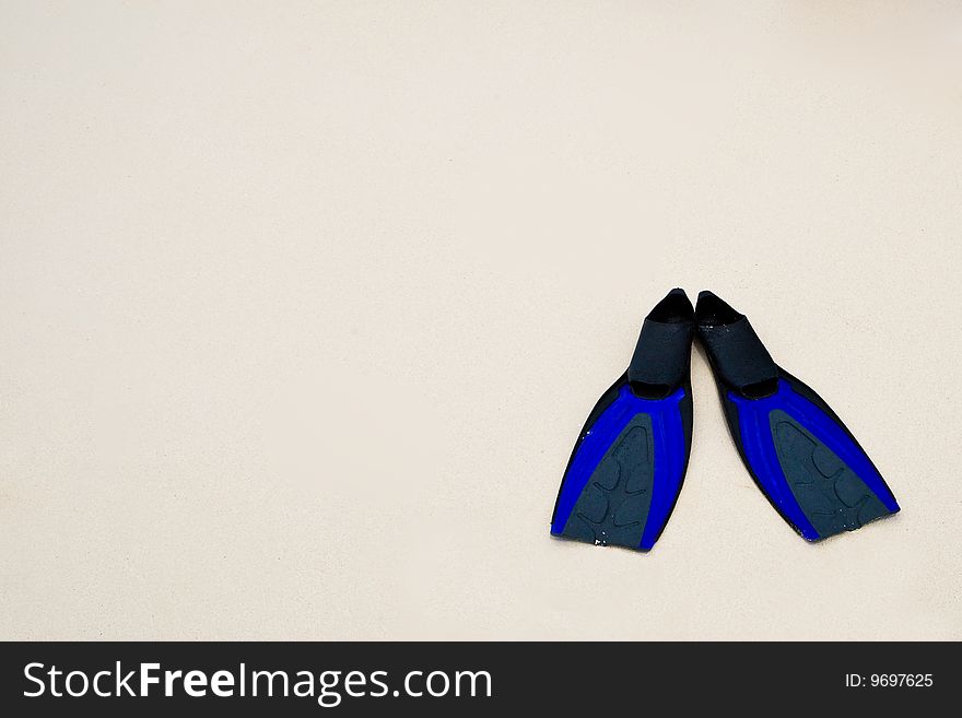 Two blue flippers on the white sand beach