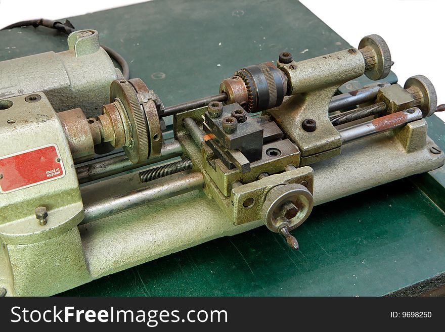 Small portable metal lathe on green board isolated closeup. Small portable metal lathe on green board isolated closeup