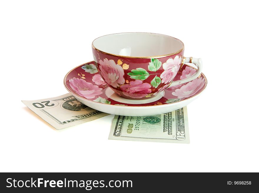 Tea Cup And Saucer On Dollar Bills Isolated