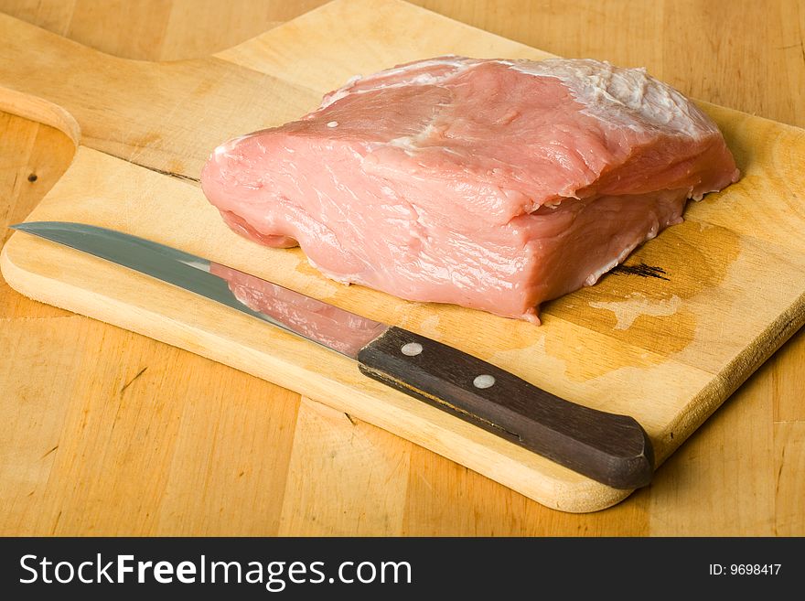 Raw pork meat on board with knife. Raw pork meat on board with knife