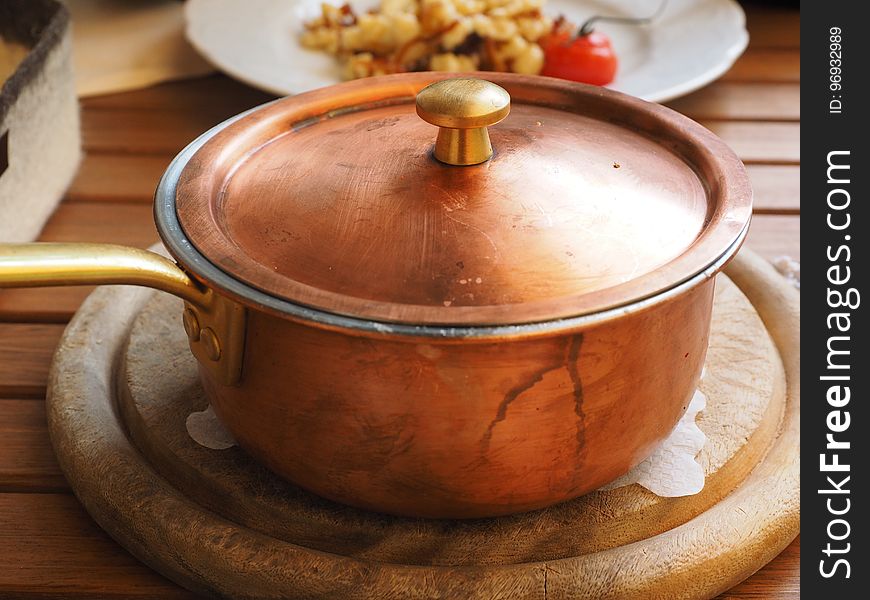 Brown Lidded Cooking Pot on Gray Round Wooden Coaster