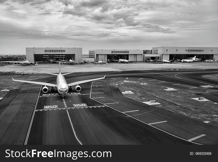 Gray Scale of Air Plane on Runway Under Cloudy Day