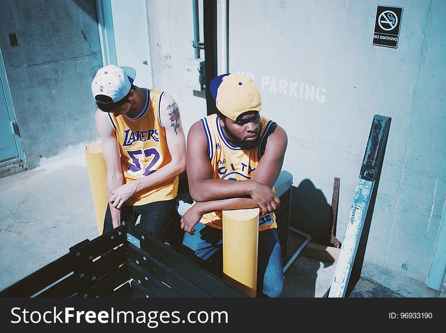 Man Wearing Yellow La Lakers Jersey Sitting Next to Man Wearing Yellow Basketball Jersey