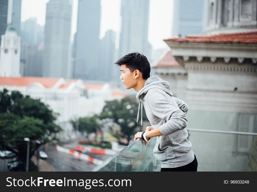 Man Wearing Grey Pullover Jacket On A Building In The City During Dayitme