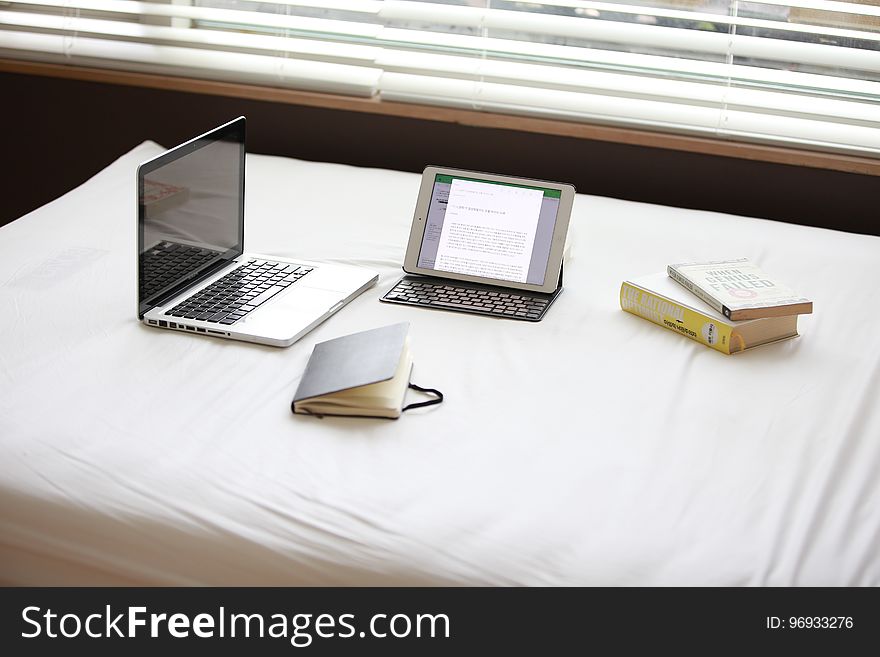 Macbook Pro over White Fabric Sheet Beside White Ipad