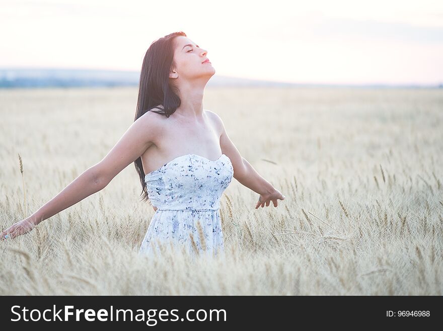 Beautiful woman with summer hat in wheat field at sunset