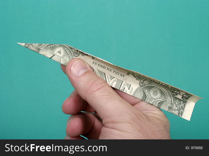 Hand holding a US dollar bill folded into a paper airplane on a green background. Hand holding a US dollar bill folded into a paper airplane on a green background.