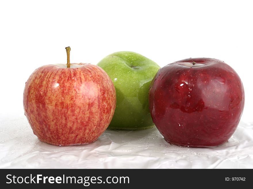 Three wet apples; one red, one green, one speckled red with water droplets on them. Three wet apples; one red, one green, one speckled red with water droplets on them.