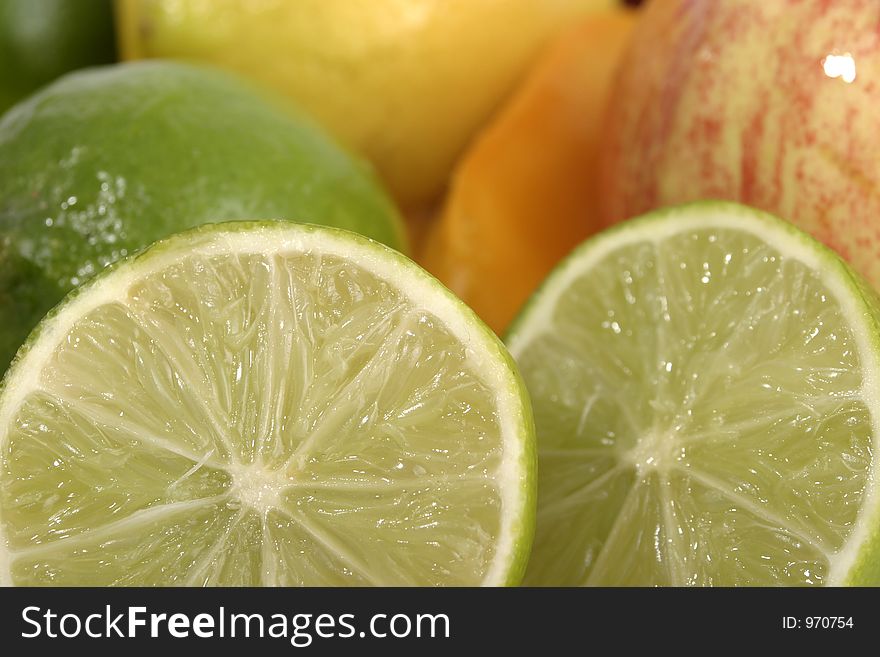 Close-up view of a sliced lime mixed in group with other fruit in the background. Close-up view of a sliced lime mixed in group with other fruit in the background.