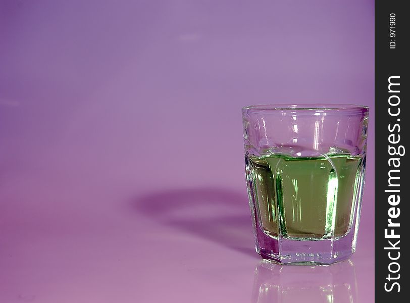 A shot glass filled with liquor and ready to shoot with a contrasty background. A shot glass filled with liquor and ready to shoot with a contrasty background.