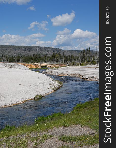 Yellowstone river flowing through the white rock formations by the mountains at the Yellowstone Natl. Park