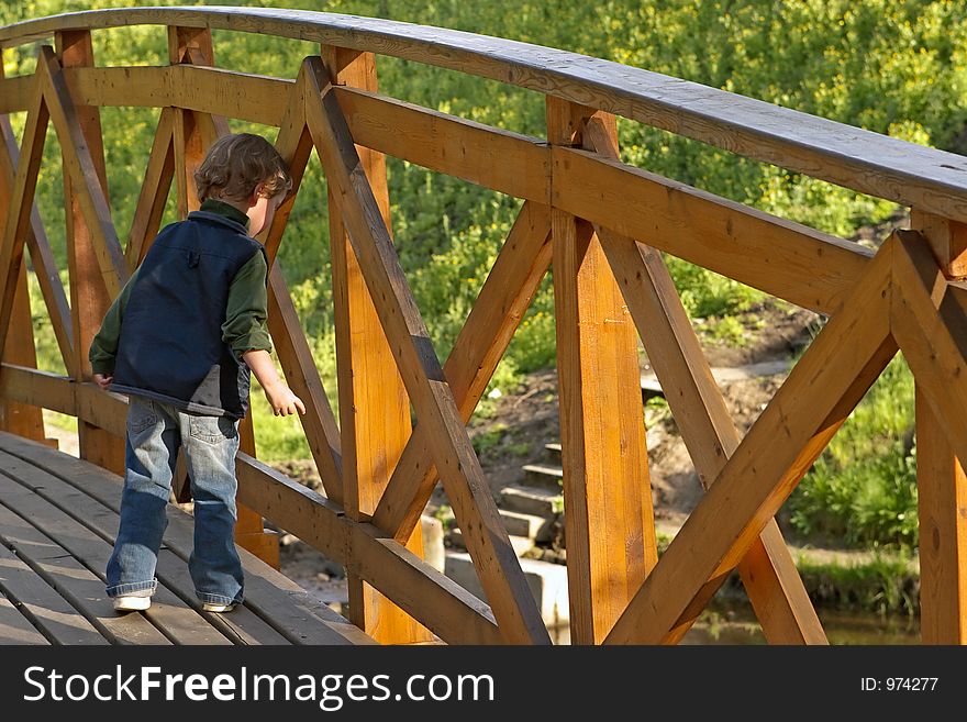 The curious kid looks downwards from the bridge. The curious kid looks downwards from the bridge