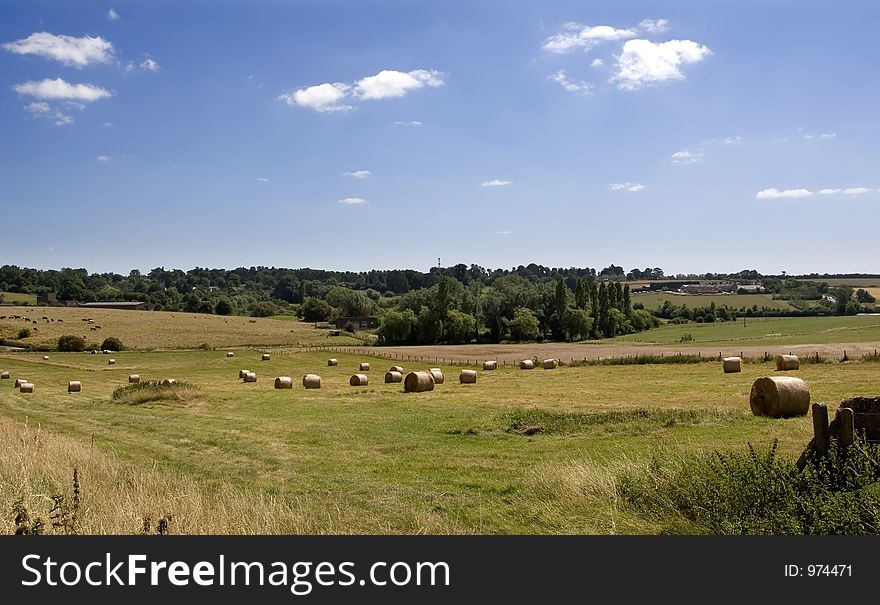 Countryside fields with hay bales and blue sky