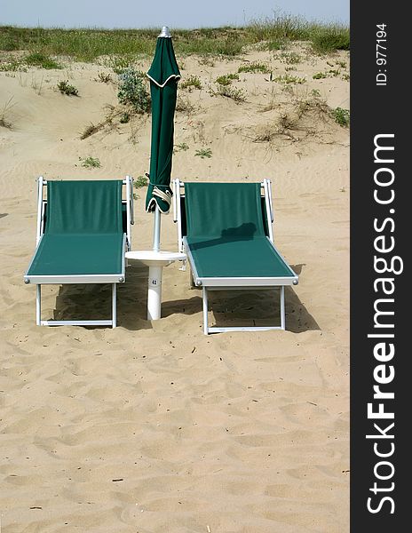Empty green chairs and umbrella sitting on an empty beach. Empty green chairs and umbrella sitting on an empty beach