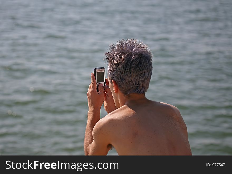 Man with cell phone looking the sea