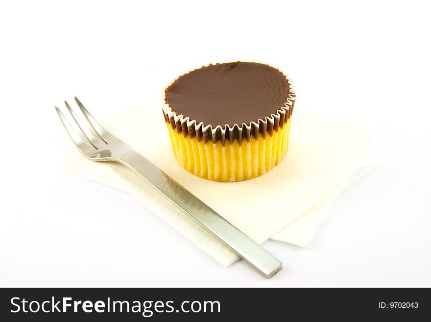 Delicious looking cup cake resting on two white napkins with a fork on a plain background