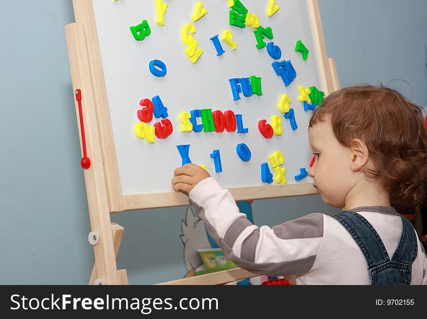 Little boy playing magnetic letters on whiteboard. Little boy playing magnetic letters on whiteboard