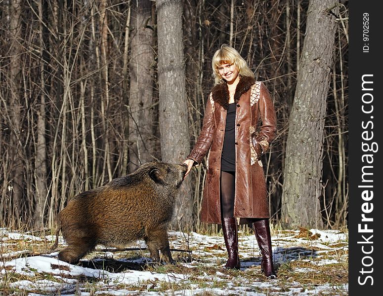 Blonde girl with wild boar at the forest