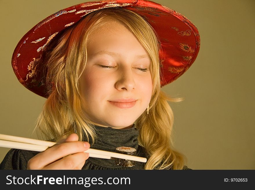 A girl with chopsticks tasting sushi. A girl with chopsticks tasting sushi