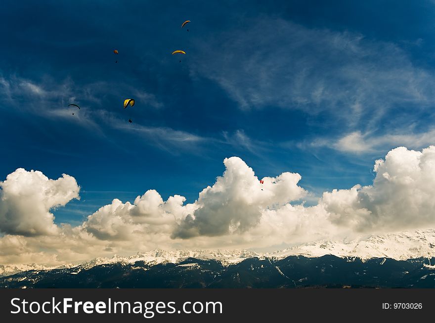 The photo of the group of parachutists living in the clouds above the mountains in Alps. Made from the parachutists take-off point. The photo of the group of parachutists living in the clouds above the mountains in Alps. Made from the parachutists take-off point.
