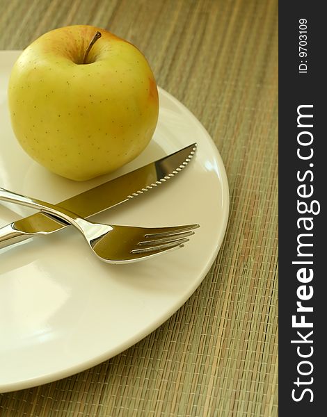 Plate with fork knife and apple, closeup