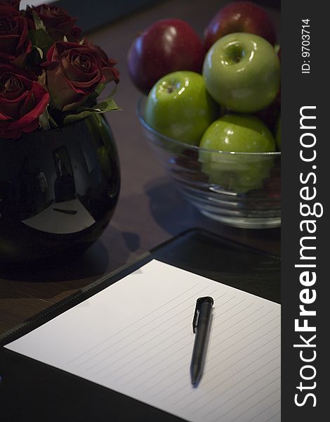 A blank corporate display book with a bowl of apples and red roses.