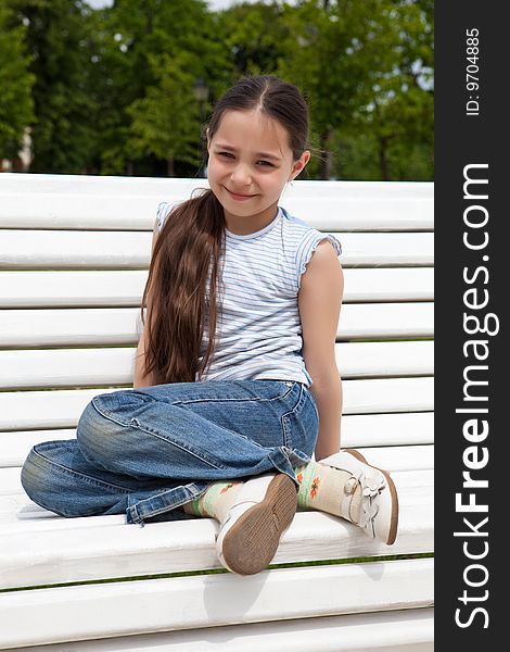 Girl sits on a white bench in park