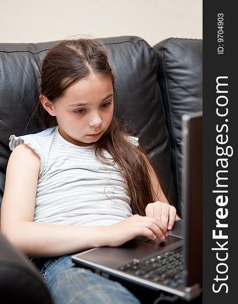 Girl sits on a sofa with the laptop in a lap
