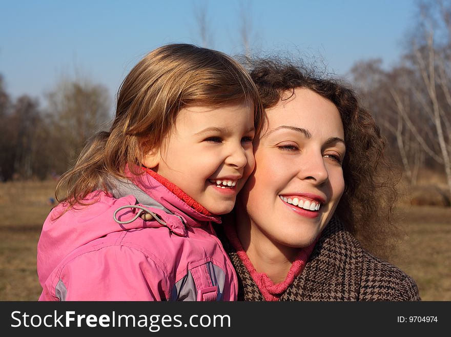 Mother with little daughter on hands outdoor in spring