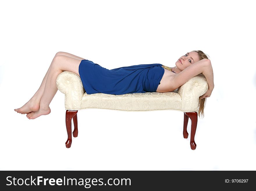 Beautiful young woman reclining on white studio bench