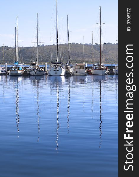 Row of yachts at the harbor in Knysna with reflection in the water on a summer day
